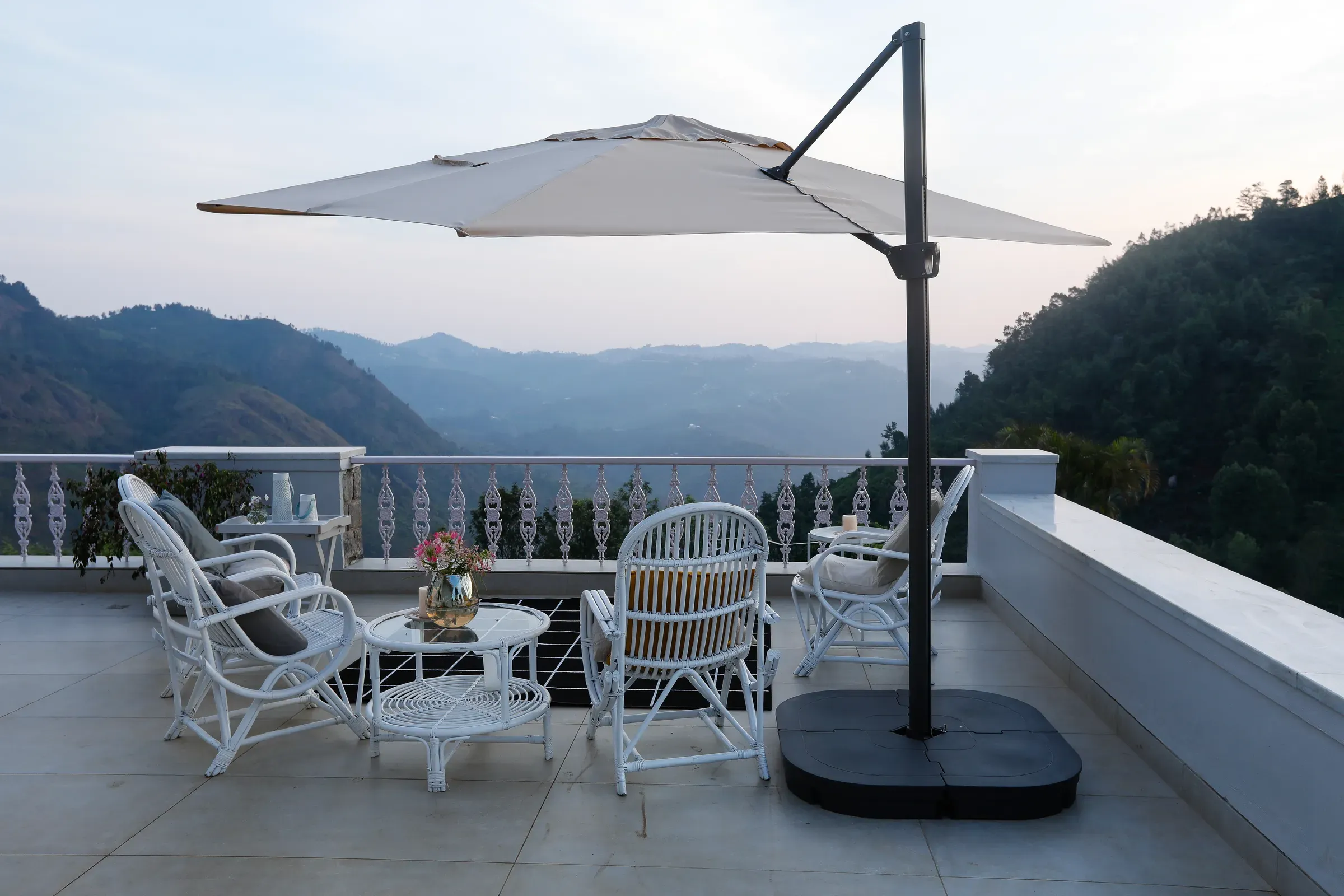 Terrace seating under a cantilevered umbrella, the Nilgiris beyond