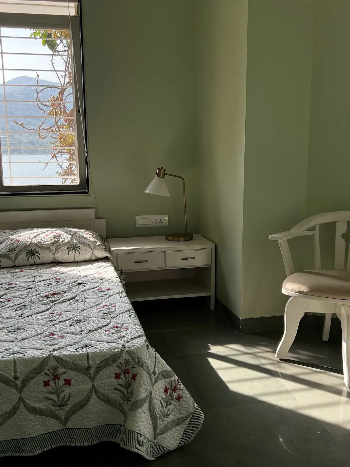A green bedroom with the lake through the window at the Malkhed house
