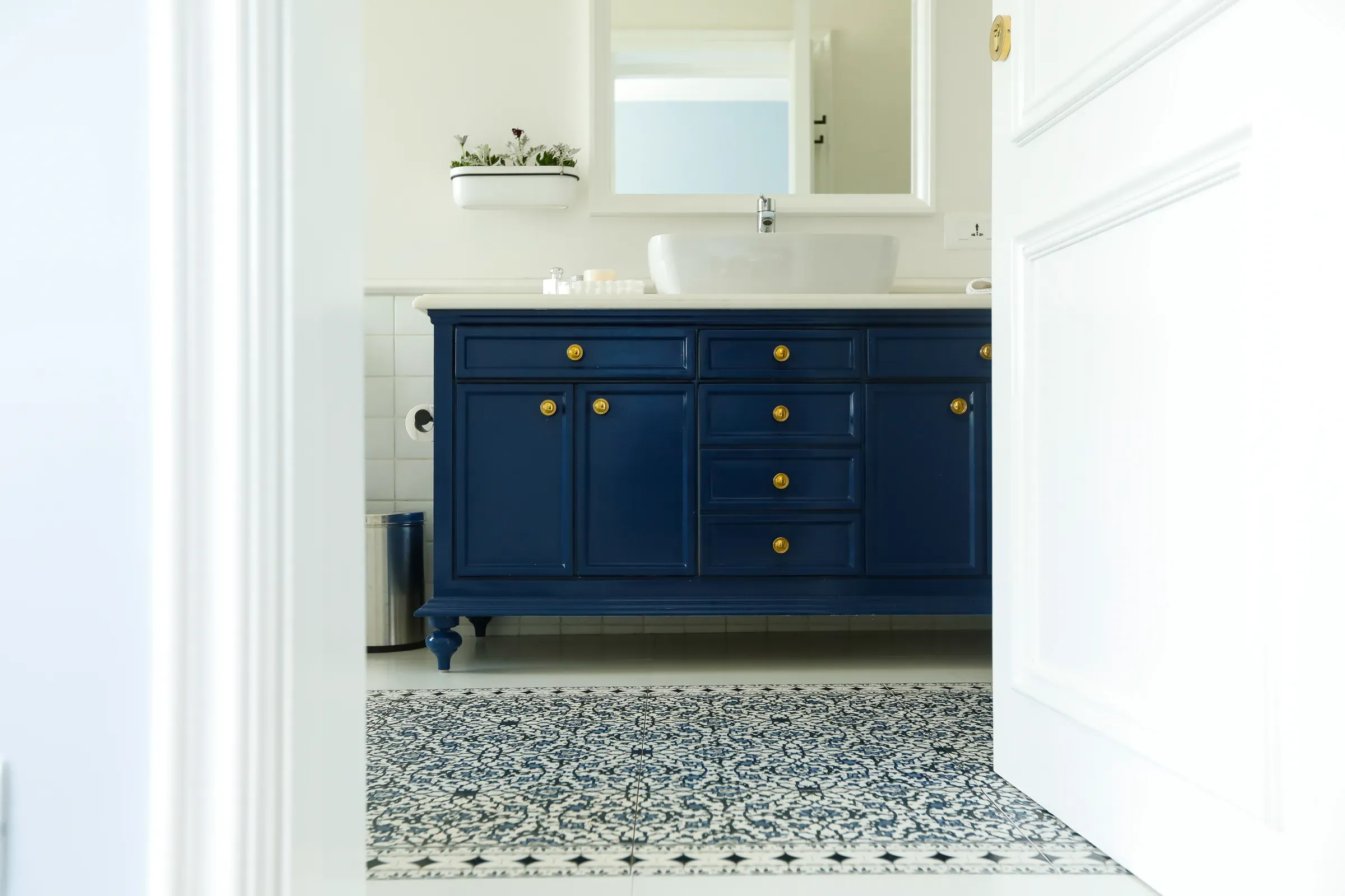 A powder room with a navy vanity and patterned tiles